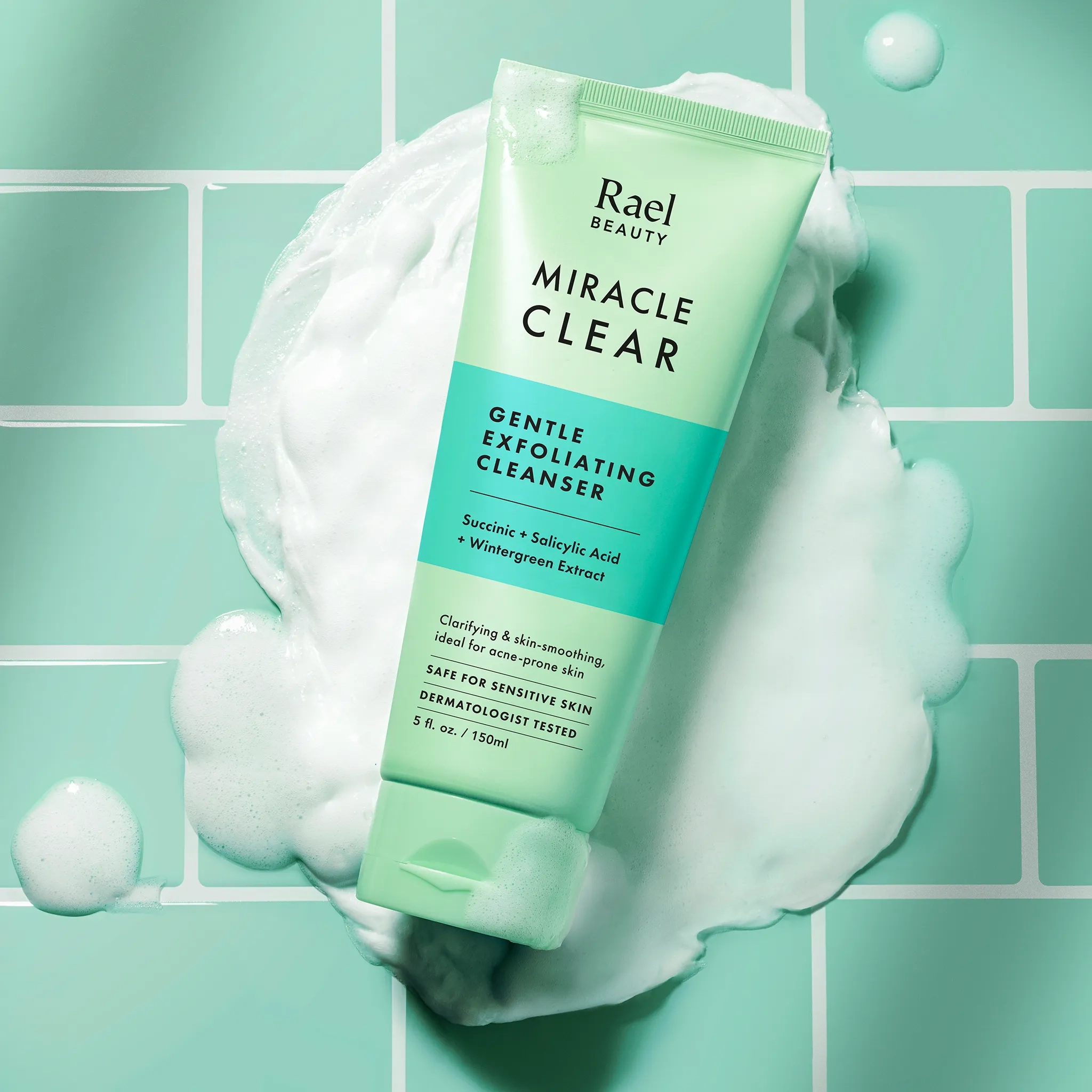 Tube of Rael Beauty Miracle Clear Gentle Exfoliating Cleanser on a green background with foam.