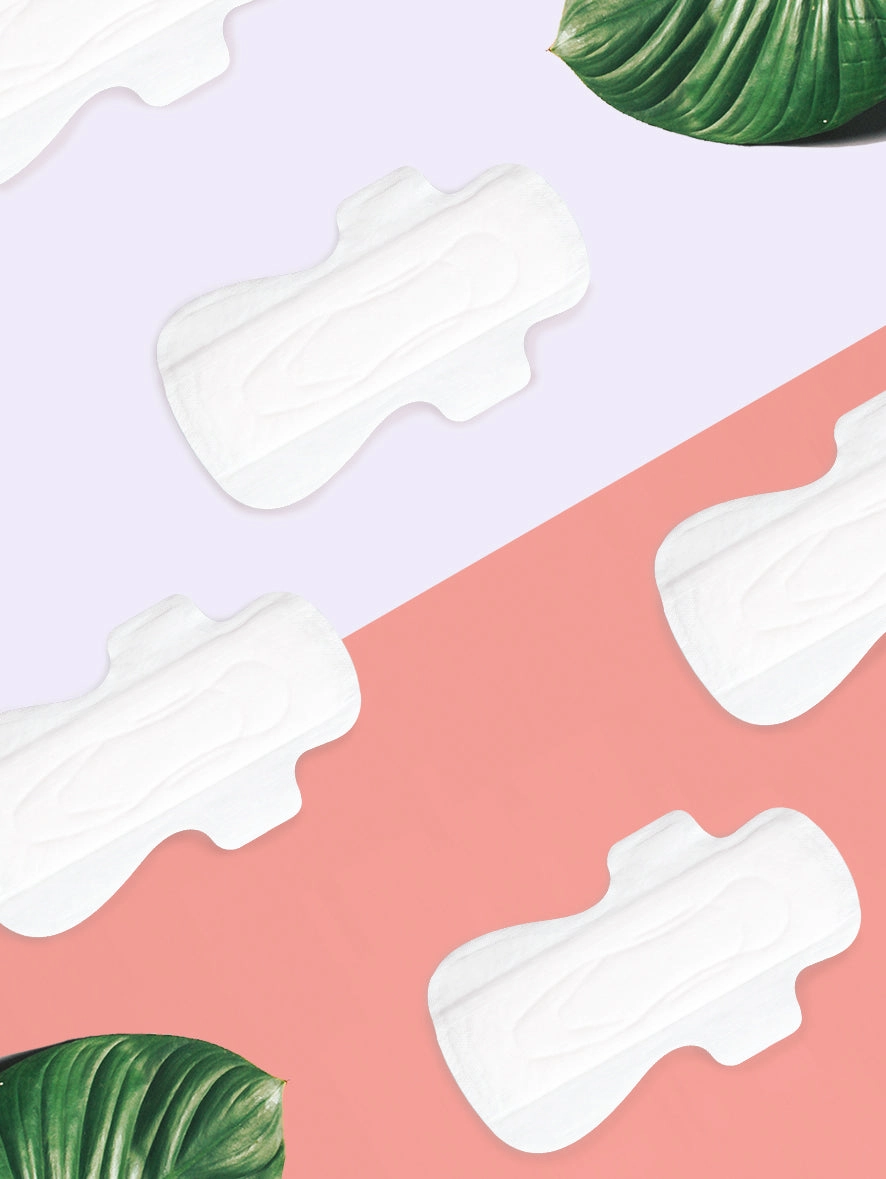 White organic cotton pads scattered on lavender and coral paper with green leaves